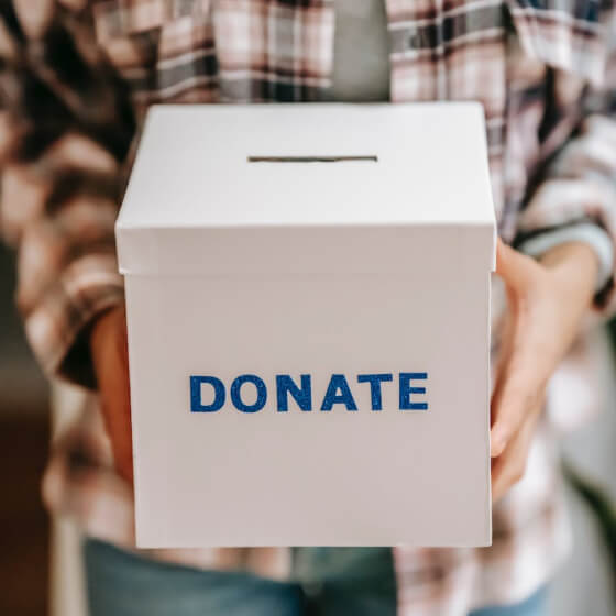 Person holding a donation box with food and essentials