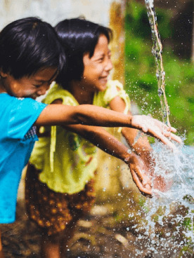 Two children enjoying playing with water outdoors